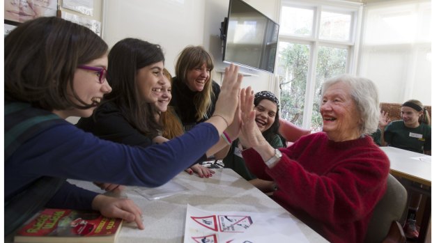 Bridging the gap: Westgarth Primary students Dulcie, Olivia, Olivia and Amy, and the Museum of Me project's Kerensa Diball  high-five aged care resident Beryl Evans. 