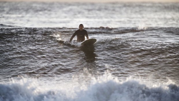Tony Abbott sits on his long board before taking off on a wave at North Steyne in 2014.