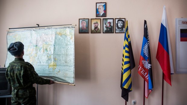 A pro-Russian rebel adjusts a map near  portraits of Vladimir Putin, Stalin, Fidel Castro, Hugo Chavez and Che Guevara at "Battalion Kalmius" headquarters in rebel-held Donetsk, Ukraine.  