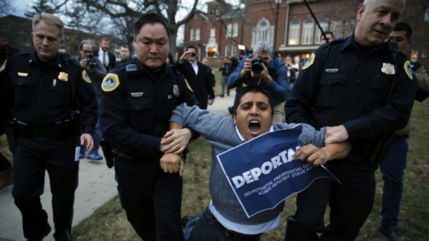 Protester Marco Malagon, bearing a sign that reads "Deportable", a reference to Republican attitudes on immigration, is dragged away from the venue for the Iowa Freedom Summit after attempting to disrupt a speech by former Texas governor Rick Perry.