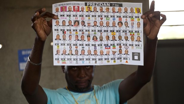 An electoral worker holds up a presidential ballot showing a vote cast for Moise Jean-Charles, of the Petit Dessalines faction, during general elections in Port-au-Prince, Haiti, on Sunday.