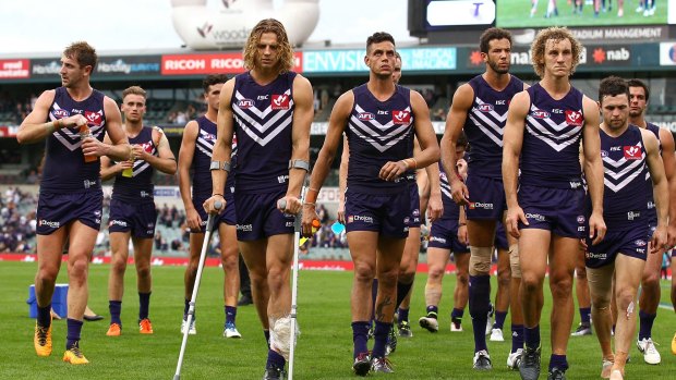 Nat Fyfe leads the Dockers  from the field on crutches after a crushing loss to Carlton.