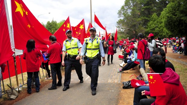 Police keep watch as protesters gather on Flynn Drive in Yarralumla as they await the arrival of China's President Xi Jinping.