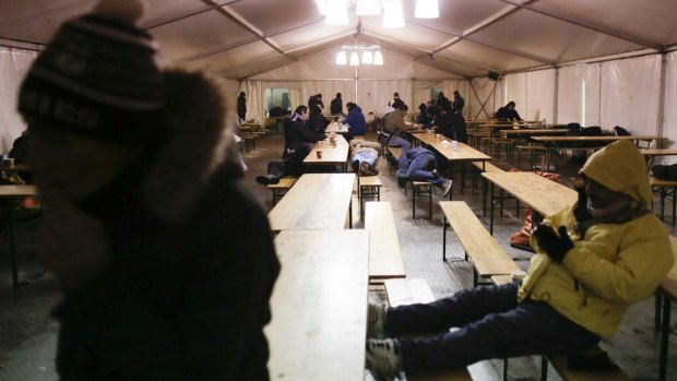 Refugeess warm themselves inside a waiting tent on a cold and snowy early morning, at the central registration center for refugees and asylum seekers in Berlin on Wednesday. 