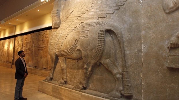 A man looks at an ancient Assyrian human-headed winged bull statue at the Iraqi Museum in Baghdad.