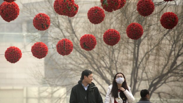 A woman wears a mask as she walks through Yuyuantan Park on a heavily polluted day in Beijing in March last year. 