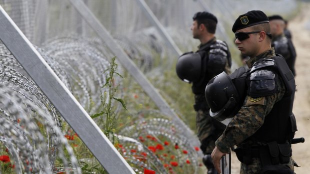 Macedonian police officers stand near the border fence during an operation of the Greek police in the makeshift refugee camp at the Greek-Macedonian border near southern Macedonian town of Gevgelija, Tuesday, May 24, 2016. Greek authorities have begun Tuesday an operation to evacuate the country's largest informal refugee camp of Idomeni, located on the Greek-Macedonian border, where more than an estimated 8,400 people have been living for months. (AP Photo/Boris Grdanoski)