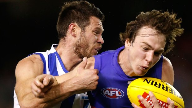 Sam Gibson of the Kangaroos and Liam Picken of the Bulldogs wrestle for possession.