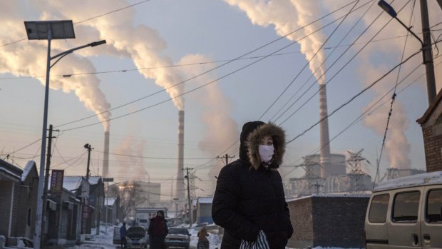 Smoke billows from stacks as a Chinese woman wears as mask while walking in a neighbourhood next to a coal fired power plant in Shanxi last month. 