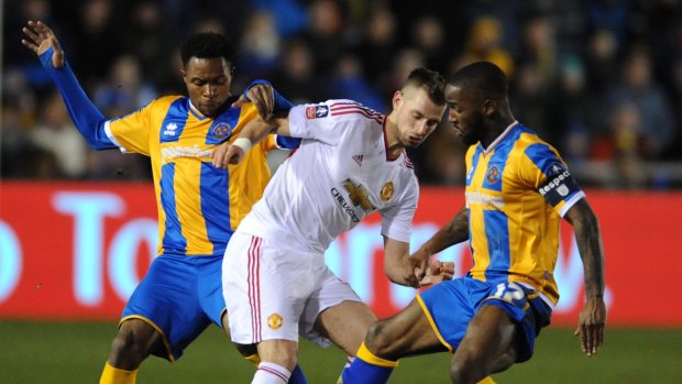 Manchester United's Morgan Schneiderlin is held back by Shrewsbury's Jean-Louis Akpa Akpro, left, and Abu Ogogo.