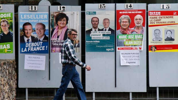 A man walks past electoral posters in Bayonne, south-western France. The newly-elected president expects to benefit from a divided opposition.