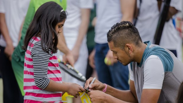 Australian tennis star Nick Kyrgios signing his autograph for eight-year-old Yalini Sundar at the Tennis Carnivale at the Weston Creek Tennis Club on Saturday.