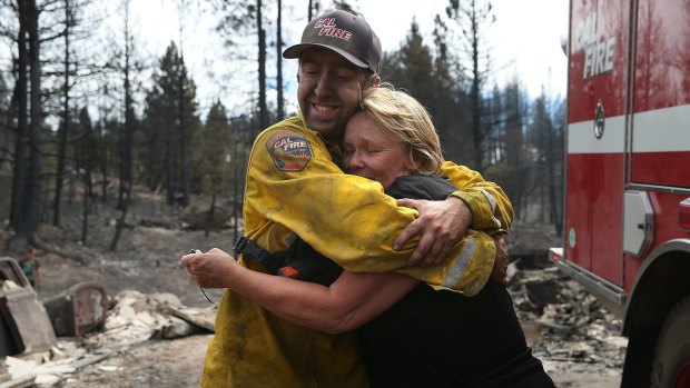 Kathy Besk hugs CalFire firefighter Tommy Janow after he found three of her rings in the ruins of her home in Weed, California. 