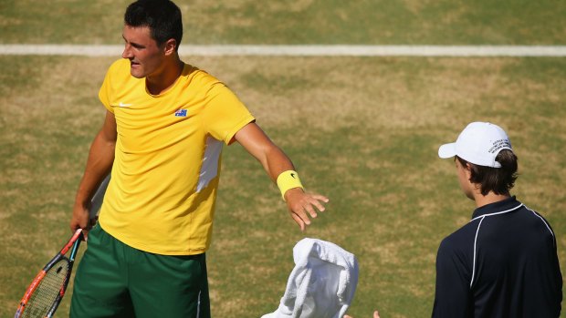 Tough day: Bernard Tomic throws his towel back during his Davis Cup loss to John Isner.