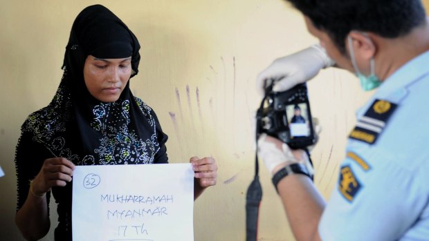 Mukharramah, a rescued Rohingya woman from Myanmar, has her photograph taken by Indonesian immigration personnel following arrival at the fishing town of Kuala Cangkoi in Aceh province.