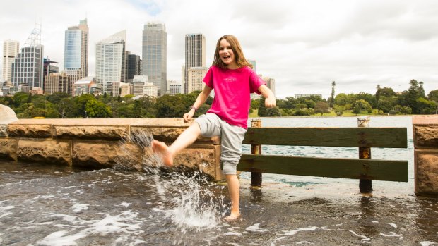 Ten-year-old Poppy Rudge from the UK wades through the water at the Botanic Gardens while her family watches.