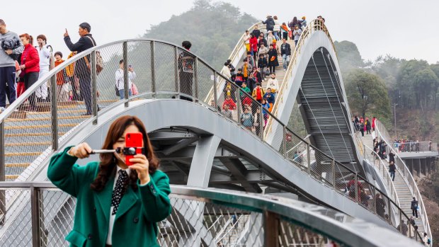 Tourists walk on Ruyi Bridge at Shenxianju Scenic Area.