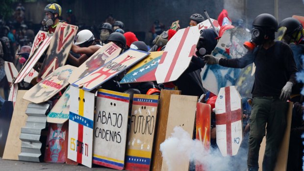 Anti-government protesters using handmade shields face off with security forces blocking a student march from reaching the Education Ministry in Caracas.