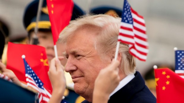 Children wave U.S. and Chinese flags as President Donald Trump arrives at Beijing Airport on Wednesday
