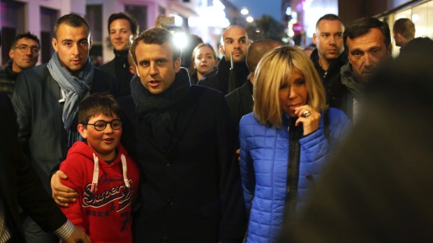 French independent centrist presidential candidate, Emmanuel Macron, center, and his wife Brigitte, right, walk in a street of Le Touquet, northern France on Saturday.