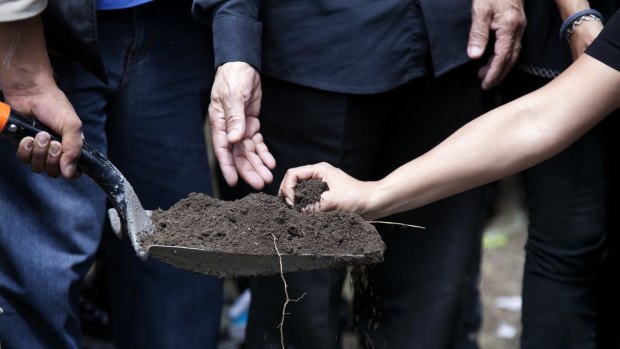 A shovel full of dirt is readied to be thrown over the casket of murdered photojournalist Ruben Espinosa.
