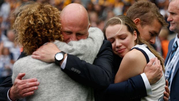 Members of the Couch family are consoled after a tribute to Paul Couch during Geelong-Hawthorn match.