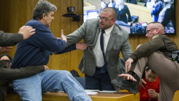 Randall Margraves, father of three victims of Larry Nassar , left, lunges at Nassar, bottom right, in court.