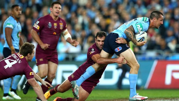 Under pressure: Mitchell Pearce is dragged down by Cam Smith.