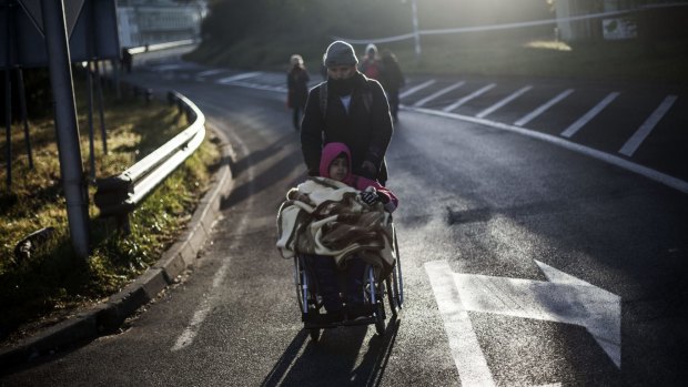An Iraqi migrant pushes his son's wheelchair on their way to Austria, at the Slovenian Austrian border near Sentijl, last weekend.