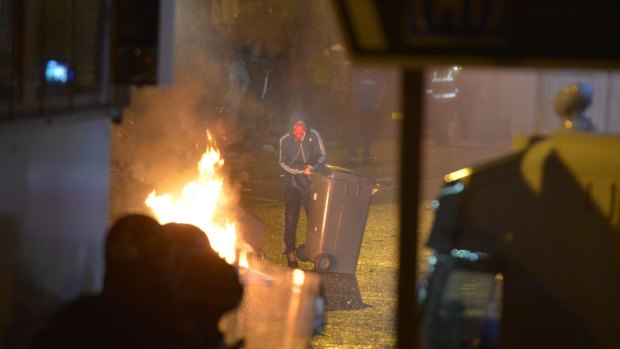A protester stands near a fire as police officers dressed in riot gear attempt to contain Loyalist rioting along the controversial Ardoyne flashpoint area on July 13 in Belfast.