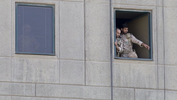 Men in military uniform stand at a window in the Iranian Parliament building.