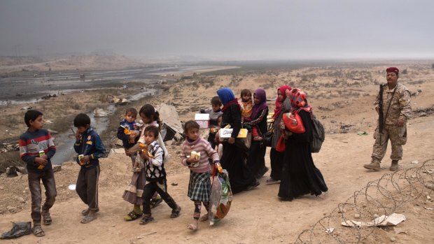 Internally displaced persons clear a checkpoint in Qayara, some 50 kilometres south of Mosul on Wednesday.