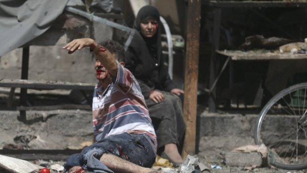 An injured man gestures as he sits near a wounded woman after air strikes on the Douma marketplace.