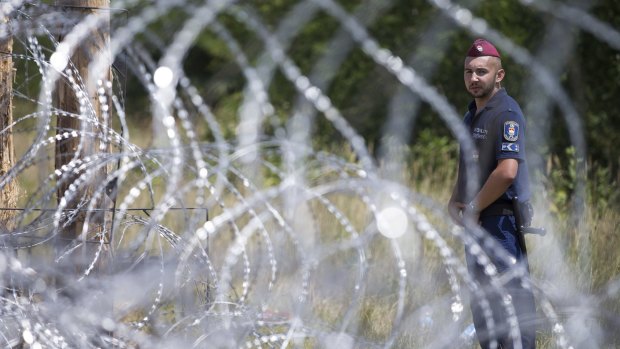 A Hungarian soldier stands next to the first portion of a fence the Hungarian military is erecting on its border with Serbia.