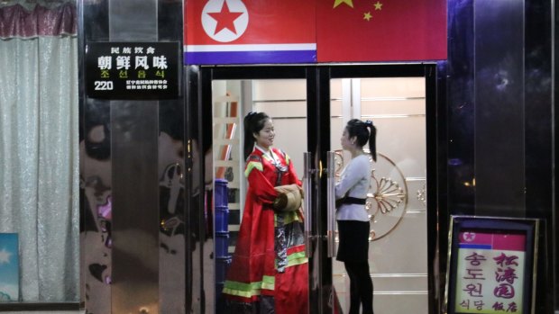 Two North Korean waitresses chat while waiting for guests at a North Korean restaurant in Dandong, China.