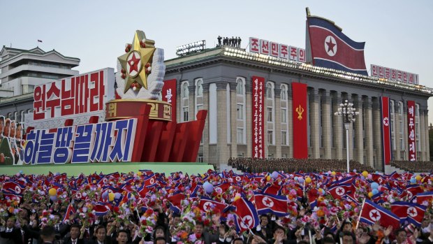 North Koreans wave their national flag as they parade in Pyongyang earlier this month. 
