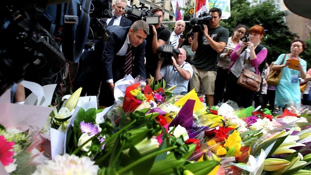 NSW Premier Mike Baird lays flowers at Martin Place after the seige where three people died early on Tuesday morning.
