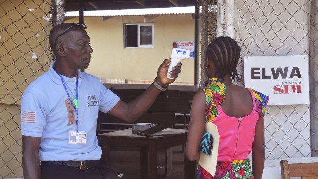 A family member of a boy who contracted Ebola has her temperature measured by a health worker before entering the Ebola clinic in Monrovia, Liberia, were the child is being treated.