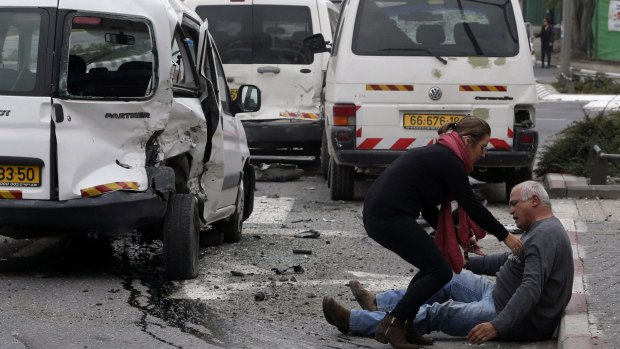 A wounded Israeli man sits on the street after Wednesday's attack by a Palestinian motorist in Jerusalem that killed one person and injured a dozen others.
