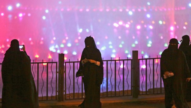 A Saudi woman takes photographs in a park during celebrations to mark the worldwide Earth Hour in Riyadh, Saudi Arabia. 