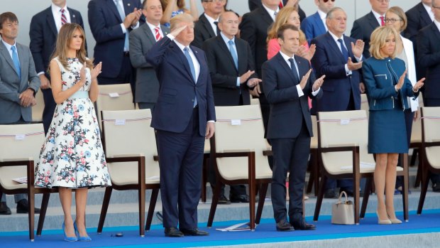 US President Donald Trump salutes while French President Emmanuel Macron, and his wife, Brigitte Macron, right, and US First Lady Melania Trump, left, applaud as they watch the traditional Bastille Day military parade.
