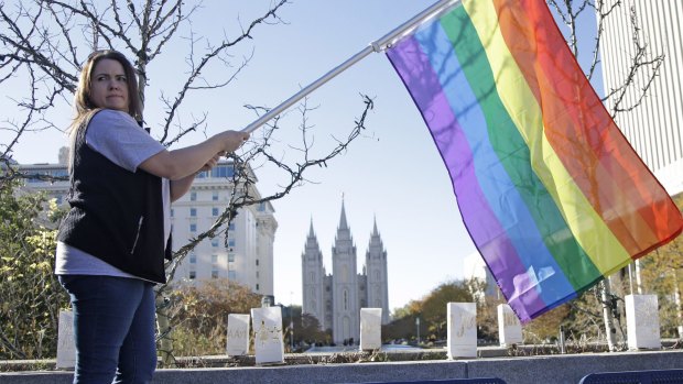 Sandy Newcomb with a rainbow flag as Mormons gather in Salt Lake City on Saturday for a mass resignation from the Church of Jesus Christ of Latter-day Saints.
