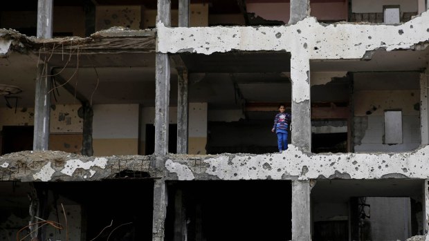 A girl looks out from an apartment building in Beit Lahiya, Gaza Strip, which was damaged during the 2014 war between Israel and Hamas. 
