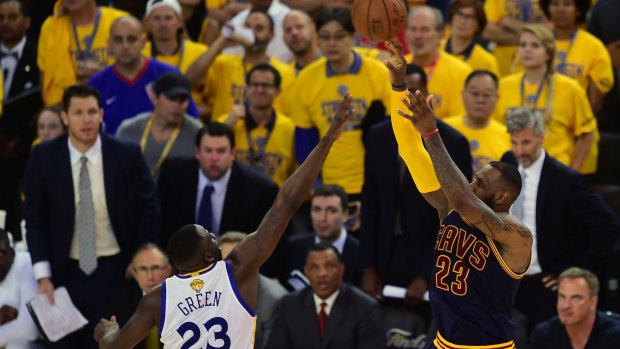 Drawcard: LeBron James shoots under pressure from Draymond Green.