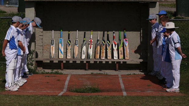 Langwarrin under-12  cricketers pay their respects to the memory of Phillip Hughes by standing their bats.