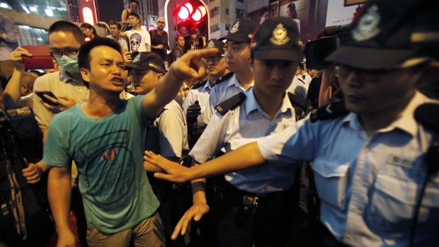 Police hold back local residents demanding pro-democracy student protesters leave the roads they have occupied in Mong Kok, Hong Kong. 