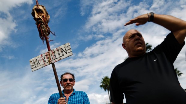 A man holds a model of Fidel Castro's head on a spike in the Little Havana neighbourhood of Miami.