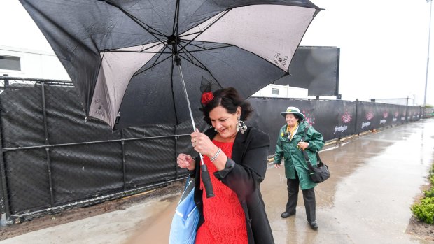 This racegoer tries to stay dry under her battered umbrella at Flemington on Melbourne Cup Day.