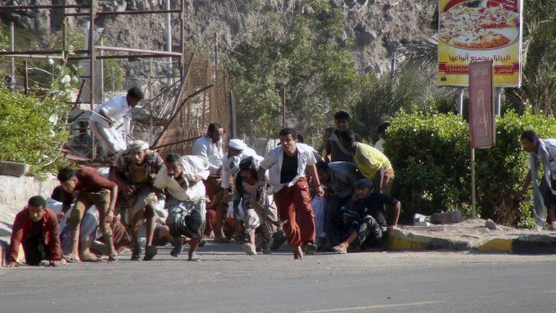 Yemenis run from gunfire at an army base in Aden.