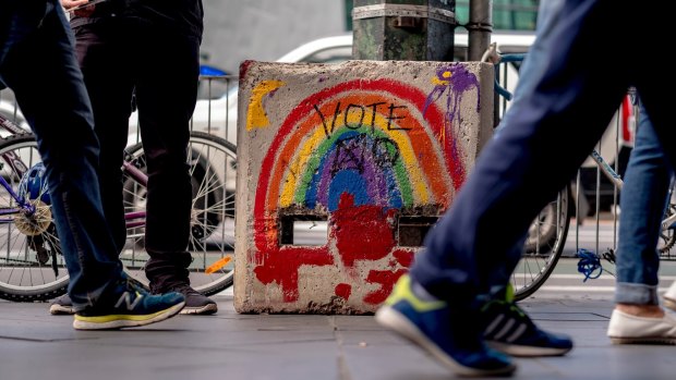 A rainbow painted in support of marraige equality with a No Vote tag on a security bollard outside Flinders Street Station.